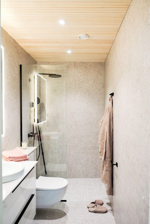 Haapapaneeli kylpyhuoneen katossa. Paneeli on rimamaista valeurapaneelia, joka luo kylpyhuoneen sisustukseen modernia ilmettä.